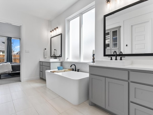 ensuite bathroom with a freestanding tub, two vanities, a sink, connected bathroom, and tile patterned flooring