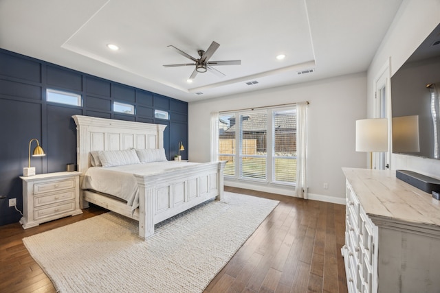 bedroom featuring a tray ceiling, dark wood-type flooring, and visible vents