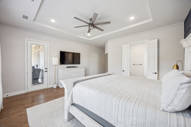 bedroom featuring dark wood-style floors, recessed lighting, arched walkways, and a tray ceiling