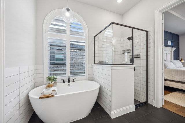 ensuite bathroom with a stall shower, a freestanding bath, tile patterned flooring, ensuite bathroom, and tile walls