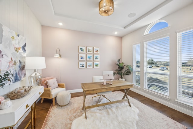 office space featuring recessed lighting, a raised ceiling, baseboards, and wood finished floors