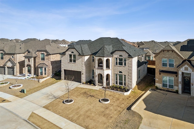 french provincial home with concrete driveway, a balcony, an attached garage, and a residential view