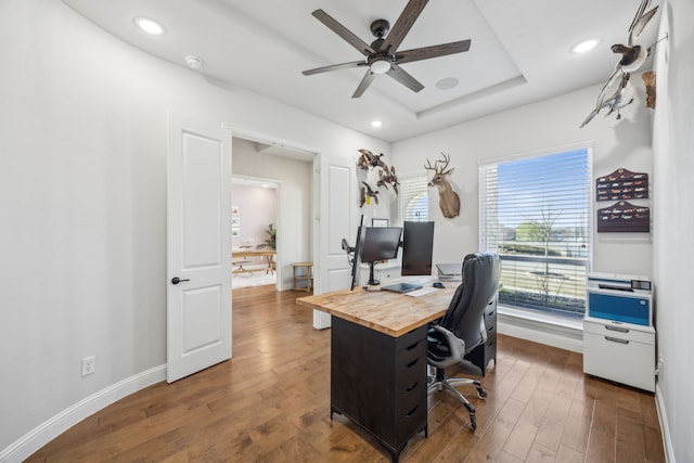 home office featuring a tray ceiling, recessed lighting, dark wood-style floors, and baseboards