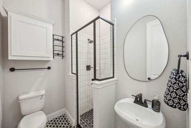 bathroom with toilet, baseboards, a stall shower, and a sink