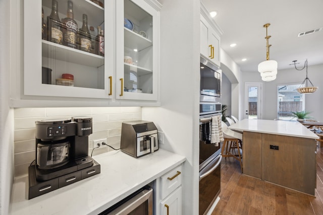 kitchen with visible vents, glass insert cabinets, appliances with stainless steel finishes, white cabinets, and dark wood-style flooring