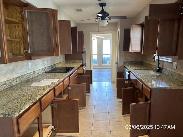 kitchen with light tile patterned floors, light stone countertops, visible vents, a sink, and black electric stovetop