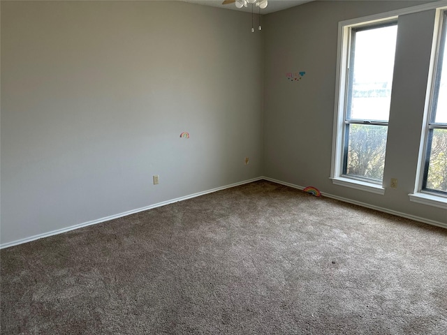 carpeted empty room featuring baseboards and plenty of natural light