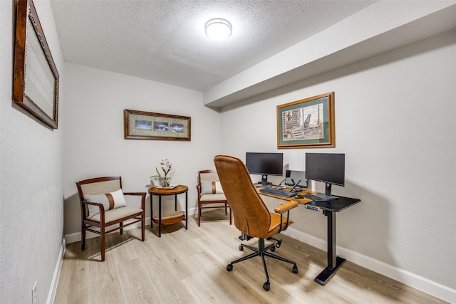 office with baseboards, light wood-style floors, and a textured ceiling