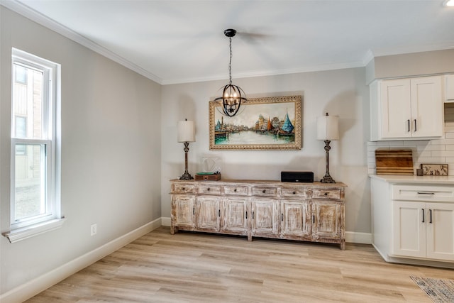 dining room with light wood-type flooring, a healthy amount of sunlight, and ornamental molding