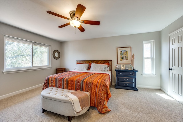 carpeted bedroom featuring multiple windows, a ceiling fan, and baseboards