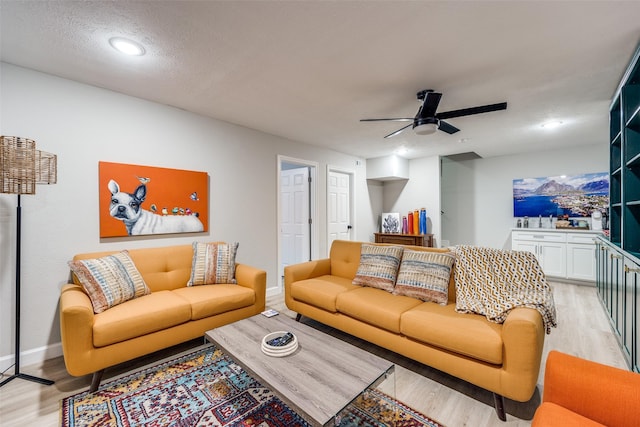 living room with light wood-type flooring, baseboards, a textured ceiling, and a ceiling fan