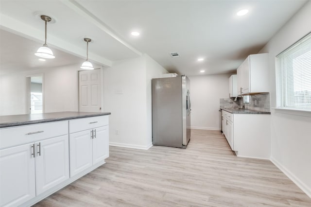 kitchen with a sink, dark countertops, white cabinets, and freestanding refrigerator