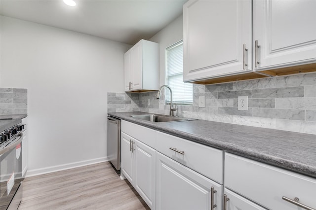 kitchen featuring a sink, tasteful backsplash, white cabinetry, stainless steel appliances, and baseboards