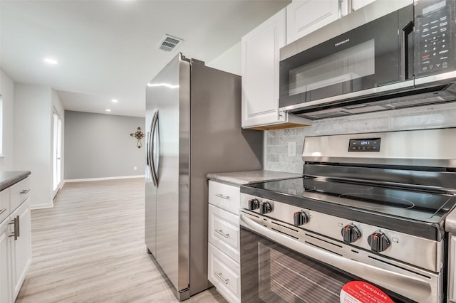 kitchen featuring visible vents, backsplash, stainless steel appliances, light wood-style floors, and white cabinetry