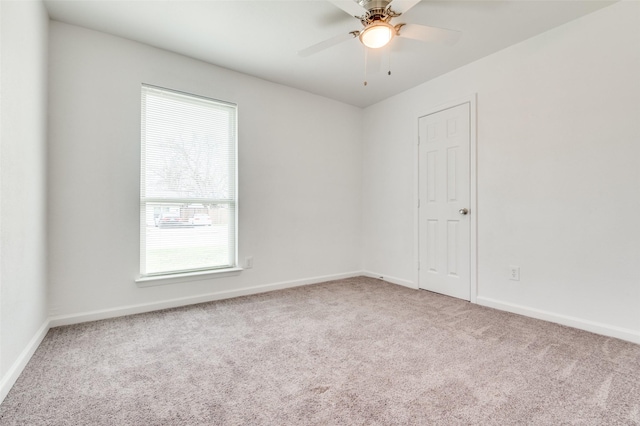 carpeted empty room with a ceiling fan and baseboards