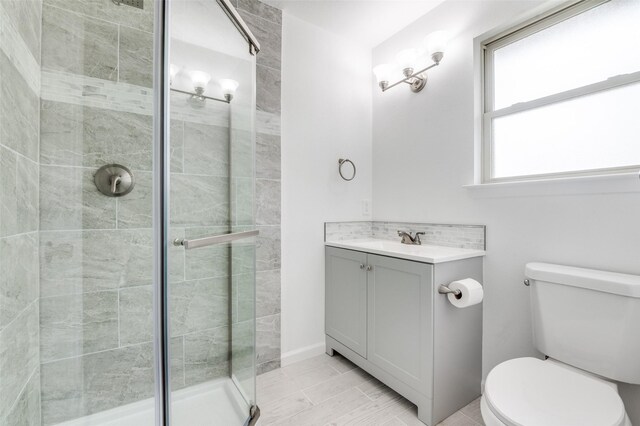 bathroom with toilet, a stall shower, and vanity