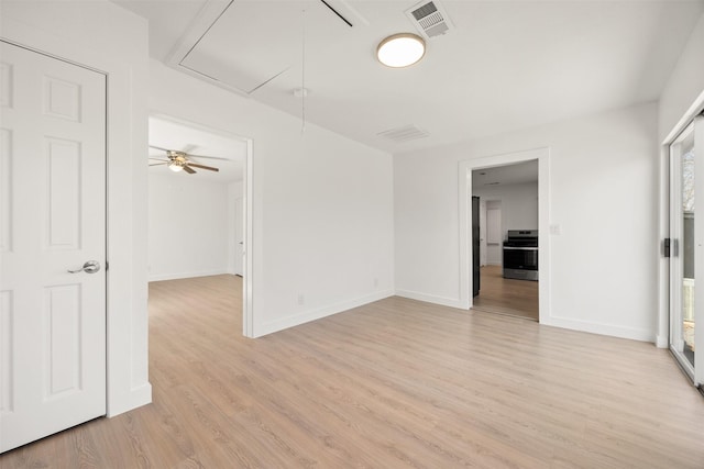 empty room featuring light wood-type flooring, visible vents, baseboards, and attic access