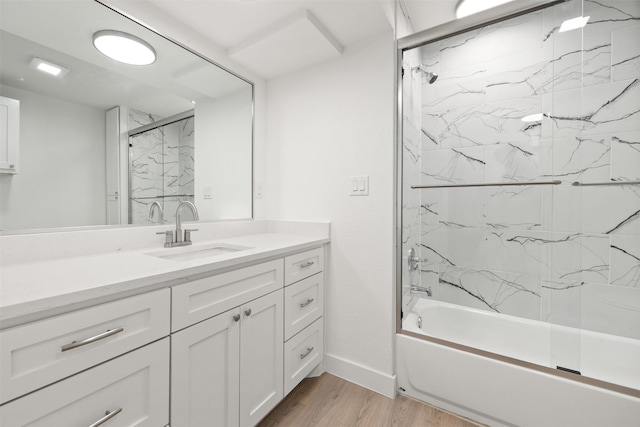 bathroom with baseboards, shower / bath combination with glass door, wood finished floors, and vanity