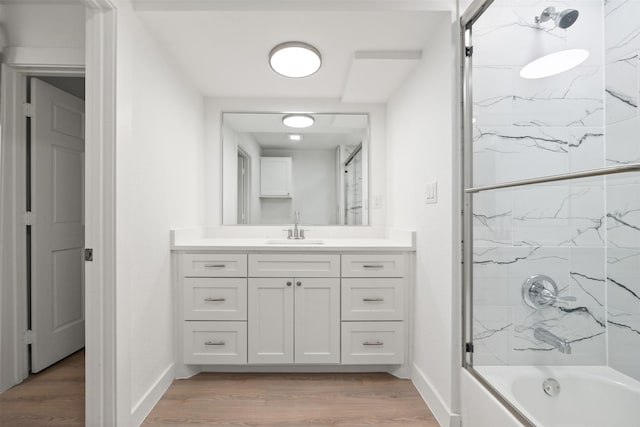 bathroom with shower / bathing tub combination, baseboards, wood finished floors, and vanity