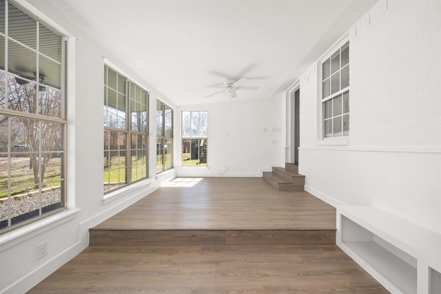 unfurnished sunroom with ceiling fan