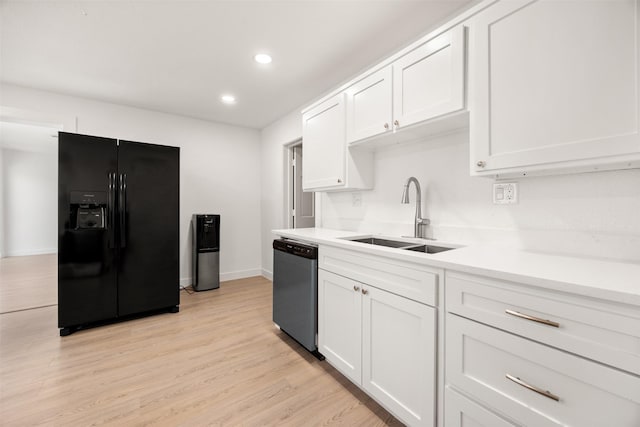 kitchen featuring a sink, light countertops, white cabinets, dishwasher, and black fridge