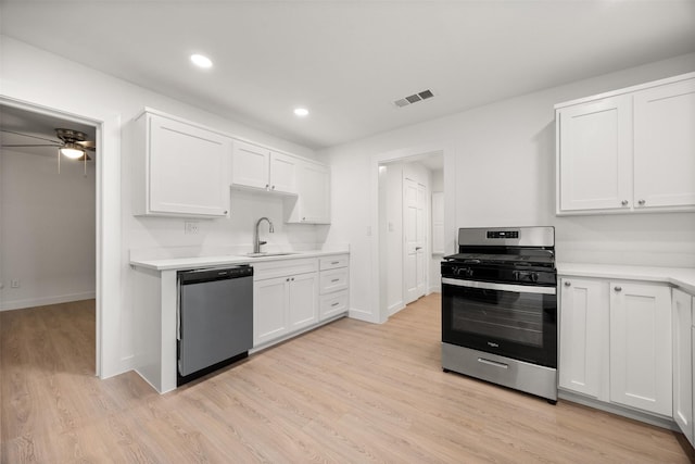 kitchen with light countertops, stainless steel appliances, light wood-style floors, white cabinetry, and a sink