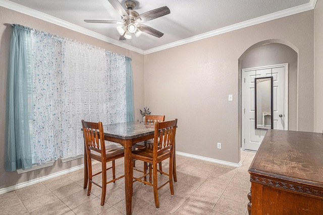 dining space with baseboards, ceiling fan, ornamental molding, light tile patterned floors, and arched walkways