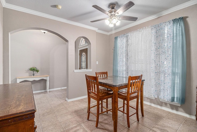 dining space with a ceiling fan, baseboards, light tile patterned flooring, arched walkways, and ornamental molding