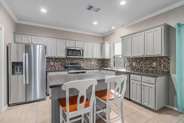 kitchen with dark countertops, visible vents, crown molding, light tile patterned flooring, and stainless steel appliances