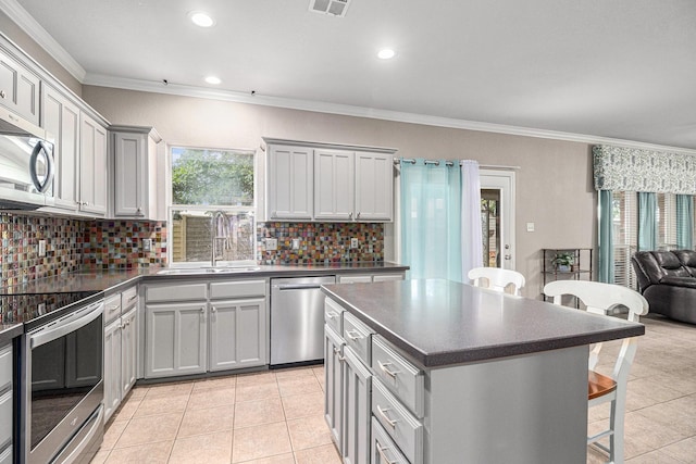 kitchen featuring a sink, stainless steel appliances, a kitchen bar, and dark countertops