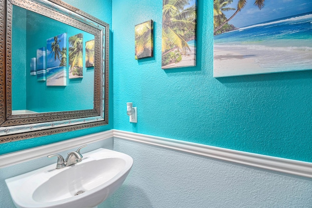 bathroom featuring a textured wall and a sink