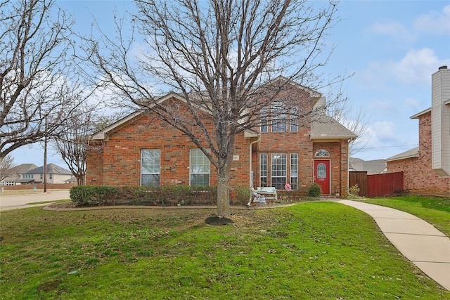 traditional-style home with brick siding, a front lawn, and fence