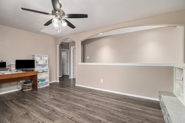 office area with baseboards, arched walkways, dark wood finished floors, and a ceiling fan