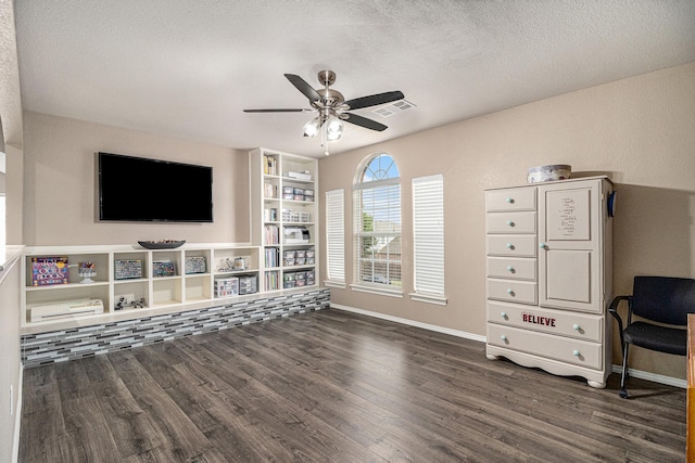 interior space featuring baseboards, visible vents, dark wood-style flooring, ceiling fan, and a textured ceiling