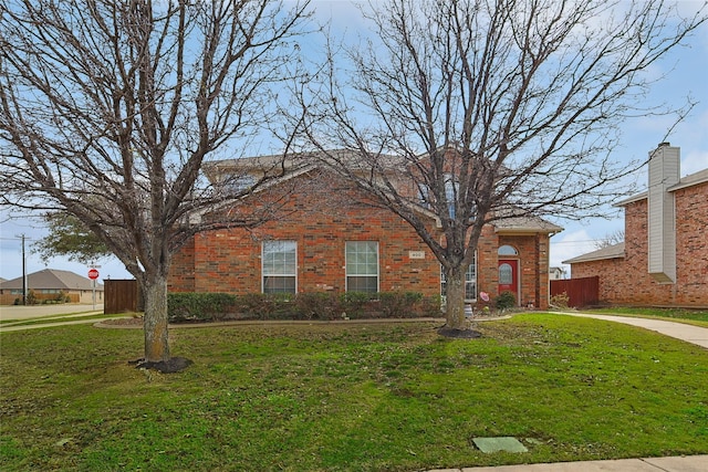 view of front of home with a front yard, fence, and brick siding