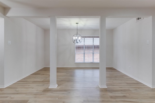 unfurnished dining area with a notable chandelier, baseboards, and light wood finished floors