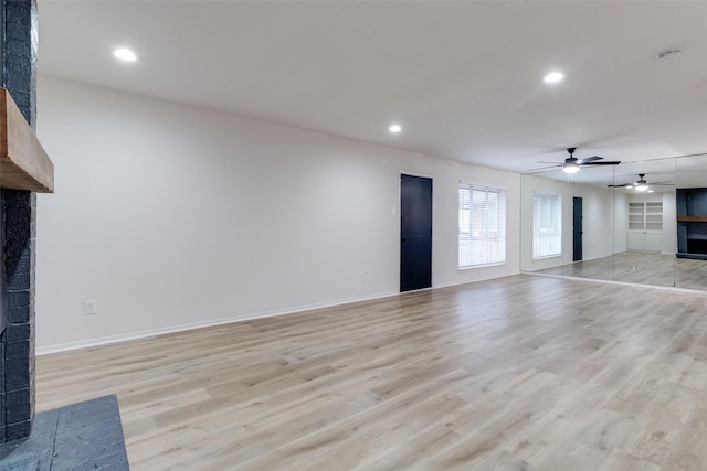 unfurnished living room with a brick fireplace, recessed lighting, light wood-style floors, and baseboards