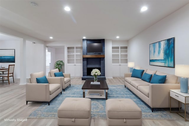 living area featuring a brick fireplace, recessed lighting, wood finished floors, and built in features