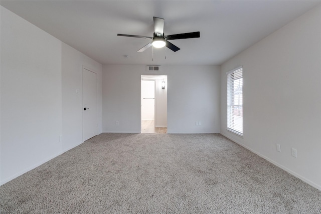 carpeted empty room with visible vents, baseboards, and a ceiling fan