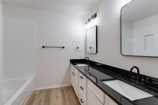 bathroom featuring double vanity, wood finished floors, baseboards, and a sink