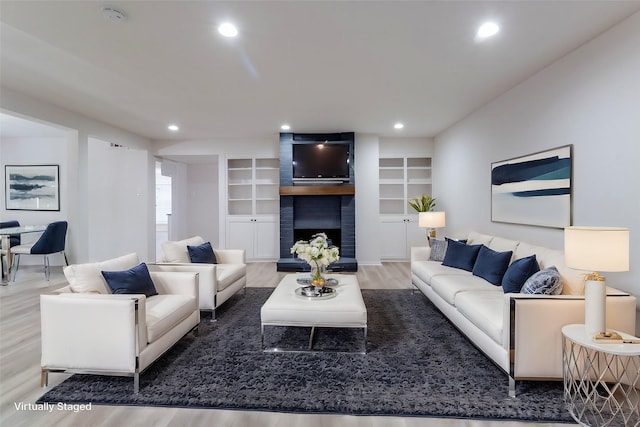 living area with built in features, recessed lighting, a fireplace, and wood finished floors