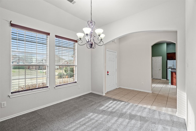 tiled empty room with arched walkways, carpet, an inviting chandelier, baseboards, and vaulted ceiling