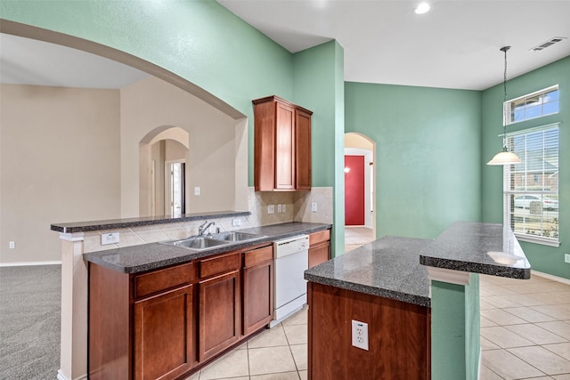 kitchen with visible vents, a sink, dark countertops, arched walkways, and white dishwasher