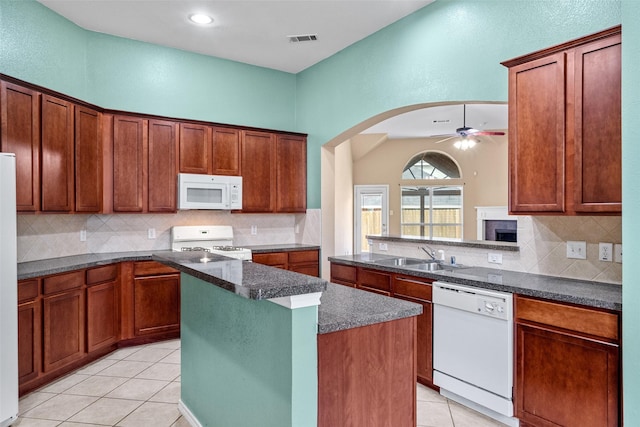 kitchen with white appliances, light tile patterned flooring, ceiling fan, a sink, and backsplash