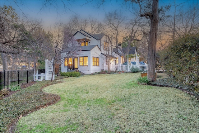 back of house at dusk featuring a yard and fence private yard