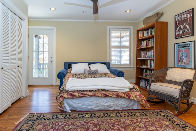 bedroom featuring a closet, crown molding, baseboards, and wood finished floors