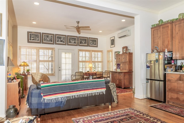 bedroom featuring a wall unit AC, wood finished floors, recessed lighting, freestanding refrigerator, and ornamental molding