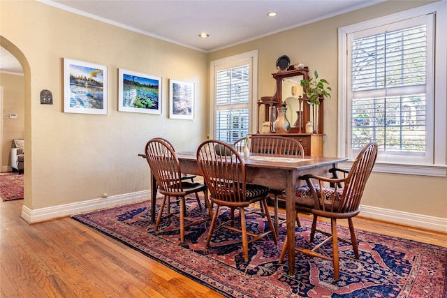 dining room with arched walkways, a healthy amount of sunlight, and crown molding