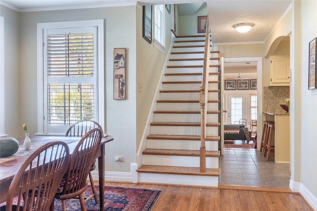 staircase with baseboards, wood finished floors, and ornamental molding