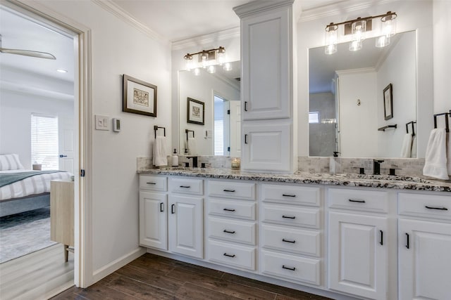 full bath with double vanity, connected bathroom, wood finished floors, and crown molding